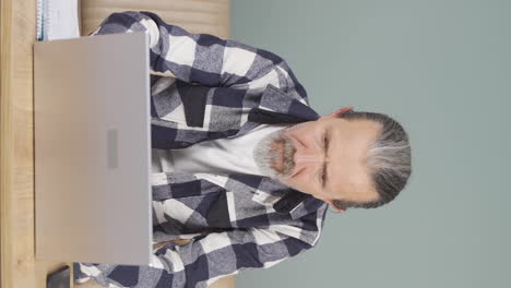 Vertical-video-of-Concentrated-old-man-working-on-laptop.